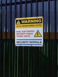 Close-up of warning sign on metal fence