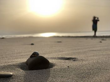 Man on beach against sky during sunset