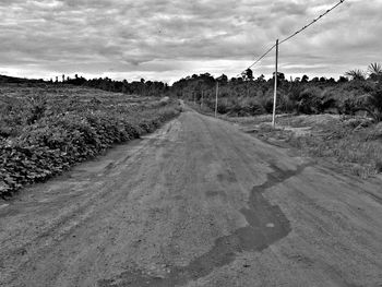 Road passing through landscape against cloudy sky