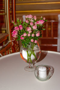 Pink roses in vase by tea light candle at table