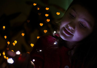 Close-up portrait of girl with illuminated christmas lights