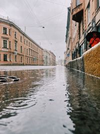 Wet road amidst buildings in city
