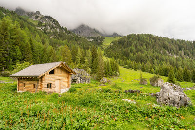 House amidst trees and mountains against sky