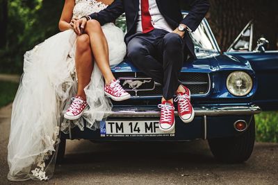 Low section of people sitting by car