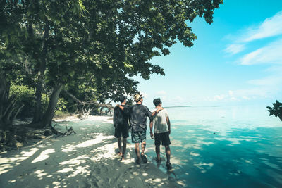 Rear view of people standing by sea against sky