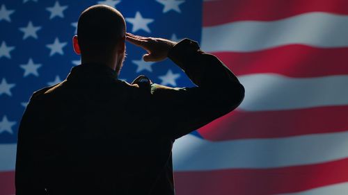 Side view of man standing against american flag