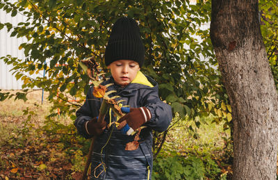 Child helps to clean up the leaves in the backyard garden. 