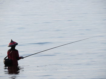 Rear view of man fishing in water
