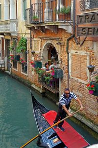 Man sitting on boat in canal along buildings