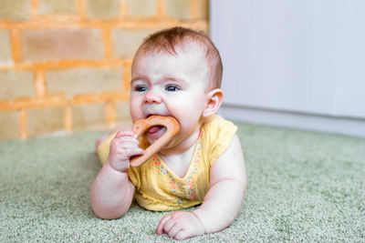 Cute little caucasian baby girl playing with wooden teething toy. eco-friendly toys for kids.