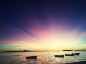 Boats in sea at sunset