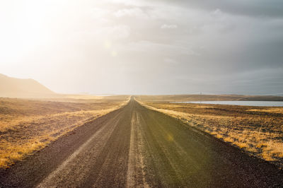 Road amidst field against sky