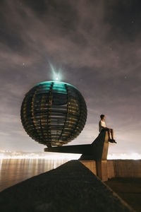 Reflection of man in water against sky at night