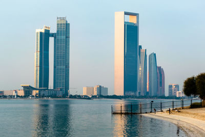 Modern buildings by river against sky in city