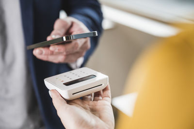 Hand of businessman paying with smart phone on card reader machine