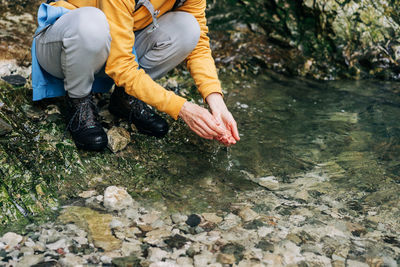 Hiker woman washes her hands in a mountain stream.