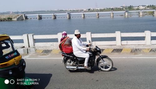 Rear view of people riding motorcycle on road