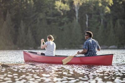 People sitting on boat against trees