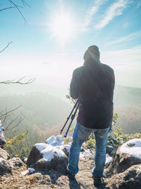 Rear view of man standing on mountain against sky