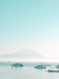 Boats moored in sea against clear sky