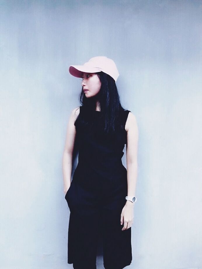 standing, clothing, three quarter length, one person, young women, fashion, young adult, lifestyles, wall - building feature, women, hat, front view, real people, black color, leisure activity, adult, casual clothing, beauty, hairstyle, beautiful woman, contemplation