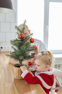 Cute girl playing with christmas tree at home
