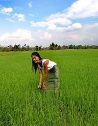 Young woman smiling in field against sky