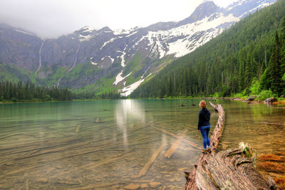 Rear view of woman standing by lake