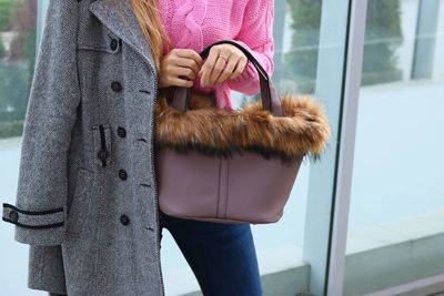 Midsection of woman holding bag while standing indoors