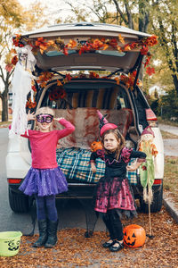 Portrait of cute girls standing by car