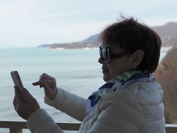 Portrait in profile. an elderly woman uses a cell phone, takes a selfie from the balcony 