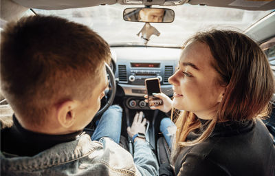 Young trendy couple discussing their route in the car with phones in hand modern navigation 