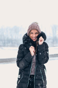 Young woman wearing hat standing against snow during winter