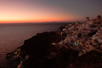 High angle view of buildings by sea against sky during sunset