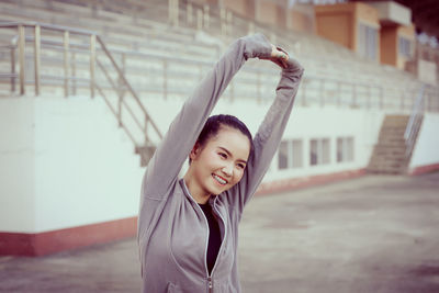 Young woman stretching while standing against built structure