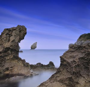 Scenic view of rocks in sea against blue sky