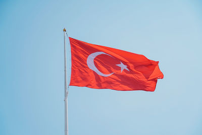 Low angle view of flag against clear blue sky