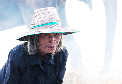 Portrait of woman wearing hat against elephant on land