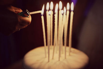 Cropped hand lighting candles on birthday cake