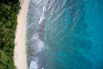 Drone field of view of empty coastline and waves meeting beach praslin, seychelles.