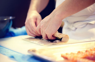 Midsection of chef preparing sushi in restaurant