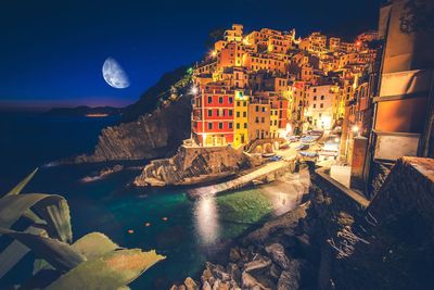 Aerial view of city by sea at night