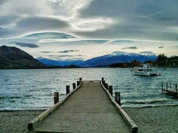 Pier on sea against cloudy sky