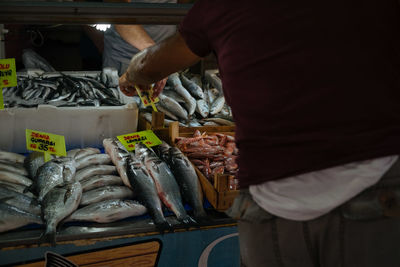 Man feeding fish for sale at market