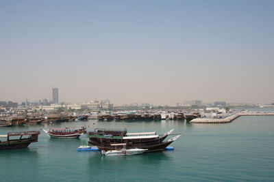 Boats moored in city against clear sky