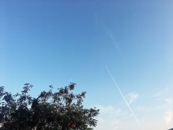 Low angle view of vapor trail against clear blue sky