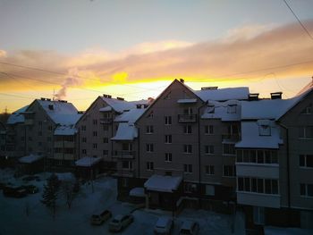 Houses and buildings against sky during sunset