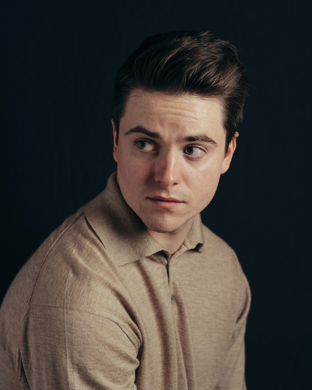 studio shot, portrait, looking at camera, one person, indoors, black background, headshot, front view, young adult, young men, handsome, serious, confidence, close-up, cut out, gray, beautiful people, casual clothing, human face