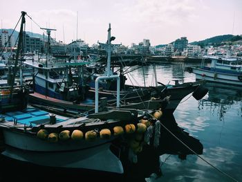 Fishing boats moored at harbor in city