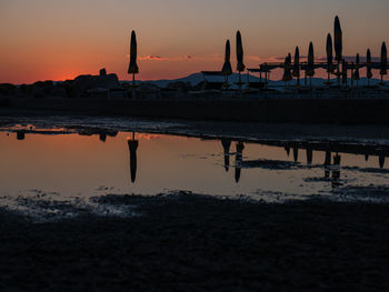 Silhouette people on beach against sky during sunset